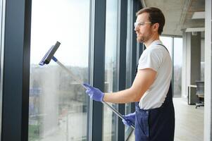 un dipendente di un' professionale pulizia servizio lavaggi il bicchiere di il finestre di il costruzione. vetrina pulizia per negozi e imprese. foto