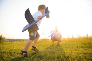 papà con il suo figlio a tramonto nel natura. un' padre giochi con giocattolo aeroplani con il suo figlio a tramonto. Il padre di giorno foto