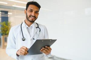 ritratto di fiducioso asiatico indiano medico medico in piedi a ospedale edificio foto