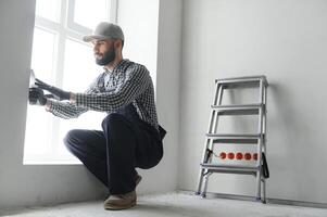 intonacatore nel blu Lavorando uniforme intonacatura il parete in casa foto