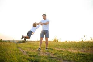 Il padre di giorno. papà e figlio giocando insieme all'aperto su un' estate. contento famiglia, padre, figlio a tramonto. foto