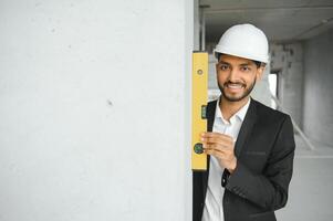 asiatico ingegnere bello uomo o architetto con bianca sicurezza casco nel costruzione luogo. in piedi a moderno edificio costruzione. lavoratore asiatico uomo Lavorando progetto edificio foto