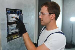 un' maschio elettricista lavori nel un' centralino con un elettrico collegamento cavo foto