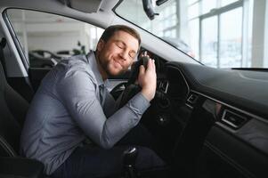 visitare auto concessionaria. bello barbuto uomo è accarezzando il suo nuovo auto e sorridente. foto