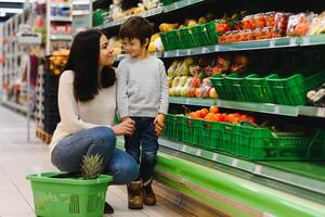 giovane madre con sua poco bambino ragazzo a il supermercato. salutare mangiare concetto foto