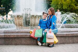 saldi, consumismo e persone concetto - contento giovane donne sua dauther con shopping borse a piedi città strada foto
