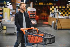 bello uomo acquisto alcuni salutare cibo e bevanda nel moderno supermercato o drogheria negozio. stile di vita e consumismo concetto. foto