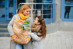 famiglia acquisti. madre e sua figlia siamo Tenere drogheria shopping Borsa con verdure. foto