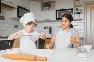 contento famiglia. madre insegnamento sua figlio Come per cucinando torta menù nel mattina. salutare stile di vita concetto.. cottura al forno Natale torta e cucinare concetto foto