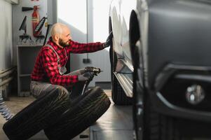 uomo riparazione un' auto ruota nel un' box auto foto