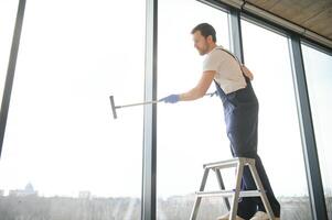 un dipendente di un' professionale pulizia servizio lavaggi il bicchiere di il finestre di il costruzione. vetrina pulizia per negozi e imprese. foto