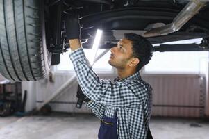 latino ispanico auto meccanico nel uniforme è l'esame un' auto mentre Lavorando nel auto servizio foto