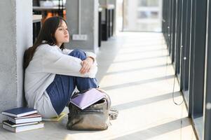 asiatico giovane ragazza alunno seduta solo con triste sensazione a scuola foto