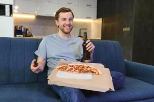 mangia Pizza mentre Guardando tv mostrare. uomo con barba al chiuso. foto