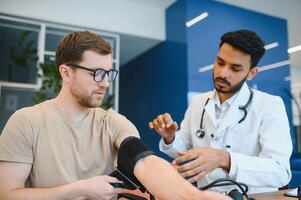 indiano medico Tenere comporre mentre misurazione dell'uomo sangue pressione foto