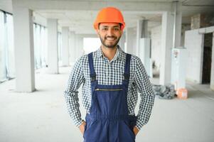 indiano costruzione luogo manager in piedi indossare casco, pensiero a costruzione luogo. ritratto di misto gara Manuale lavoratore o architetto. foto