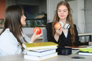 formazione scolastica. Due intelligente moderno studenti nel nero e bianca uniforme studia nel un' biblioteca seduta a un' tavolo con libri. moderno generazione. studenti. foto