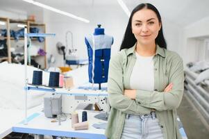 positivo giovane donna cucire con professionale macchina a officina. foto