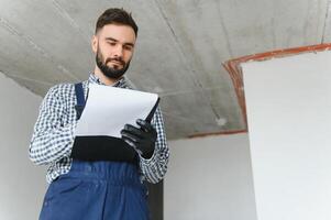 ridendo costruzione lavoratore su il sfondo di un' grigio calcestruzzo parete. ristrutturazione. posto per testo foto