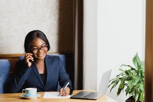 pensieroso nero donna d'affari utilizzando tavoletta computer nel caffè negozio foto