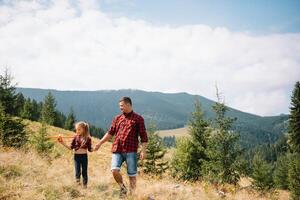 contento padre e poco bambino siamo a piedi nel il montagne. Il padre di giorno. vacanza nel il nazionale parco. foto