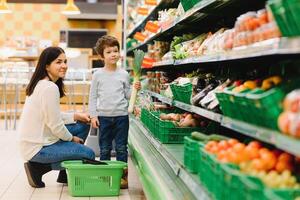 donna e bambino ragazzo durante famiglia shopping con carrello a supermercato foto