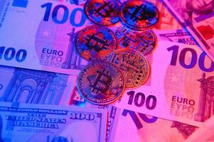 vicino su mucchio di d'oro bitcoin fisico monete su superiore di Euro, dollaro banconote sfondo, alto angolo Visualizza, selettivo messa a fuoco foto