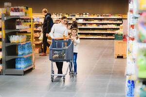 famiglia nel il supermercato. bellissimo giovane mamma e sua poco figlia sorridente e acquisto cibo. il concetto di salutare mangiare. raccogliere foto