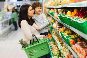 giovane madre con sua poco bambino ragazzo a il supermercato. salutare mangiare concetto foto