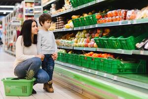 giovane madre con sua poco bambino ragazzo a il supermercato. salutare mangiare concetto foto