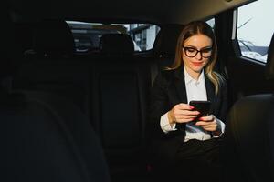 alcuni ordinare di interessante informazione. inteligente donna d'affari si siede a sedile posteriore di il lusso auto con nero interno. foto