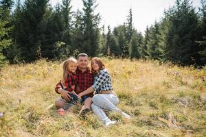 famiglia di tre persone riposo nel il montagne. essi sat giù per riposo, bevanda acqua dopo un' difficile scalata per il montagna. essi siamo stanco ma contento foto