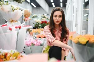 bellissimo fioraio a fiore negozio. donna Lavorando nel floreale negozio con copia spazio. riuscito fioraio sorridente foto