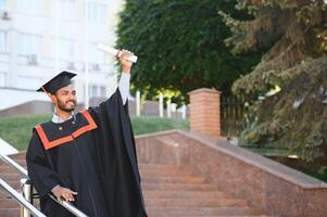 giovane indiano laureato ragazzo Tenere il suo la laurea grado convocazione cerimonia. alunno diplomato in posa. foto