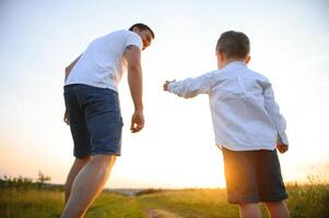 Il padre di giorno. papà e figlio giocando insieme all'aperto su un' estate. contento famiglia, padre, figlio a tramonto. foto