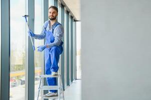 lavoratore pulizia finestre servizio su alto salire edificio foto