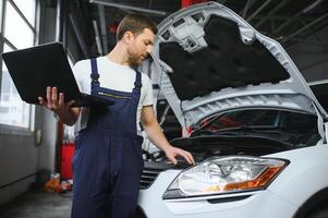 auto servizio, riparazione, Manutenzione concetto. meccanico controlli il macchina, fabbricazione diagnostica con il computer portatile a il servizio stazione. servizio Manutenzione di industriale per motore riparazione. foto