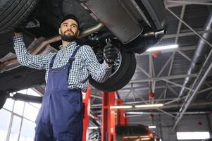 auto meccanico Lavorando sotto un' sollevato auto foto