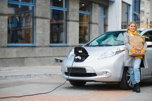 donna ricarica elettro auto a il elettrico gas stazione. foto