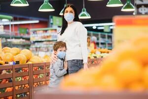 giovane donna e sua ragazzo indossare protettivo viso maschere negozio un' cibo a un' supermercato durante il coronavirus epidemico o influenza scoppio. foto