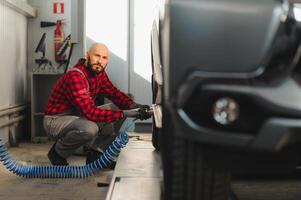 uomo riparazione un' auto ruota nel un' box auto foto