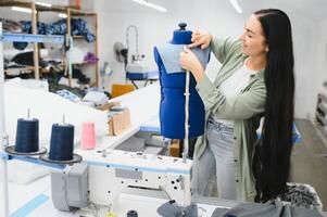 contento femmina sarta Lavorando con cucire macchina a tessile fabbrica. foto