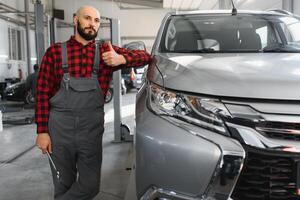 maschio meccanico Lavorando a un' riparazione negozio e Tenere utensili foto