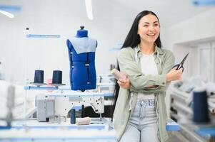 contento femmina sarta Lavorando con cucire macchina a tessile fabbrica. foto