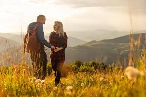 un' uomo e un' donna nel turista attrezzatura siamo in piedi su un' roccia e ammirazione il panoramico Visualizza. un' coppia nel amore su un' roccia ammira il bellissimo visualizzazioni. un' coppia nel amore è in viaggio. un' coppia su un' escursione foto