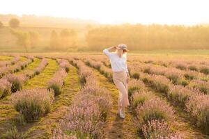 giovane donna in piedi su un' lavanda campo con Alba su il sfondo foto