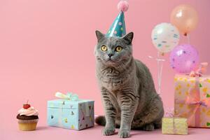 ai generato un adorabile grigio gatto nel un' festa cappello seduta accanto un' Cupcake e i regali su un' rosa sfondo. foto