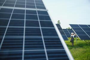 un' lavoratore passeggiate attraverso un' solare pannello azienda agricola foto