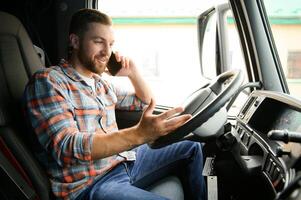 giovane professionale autista comunicare al di sopra di mobile Telefono mentre guida un' camion. foto