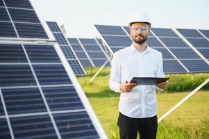 positivo barbuto maschio investitore in piedi contro fotovoltaico pannelli producendo alternativa energia. foto